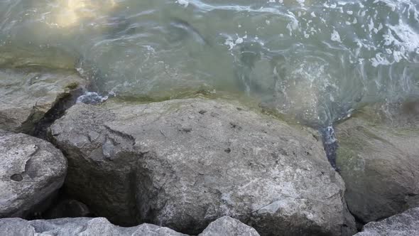 Slow motion of water waves hitting rocks at shore