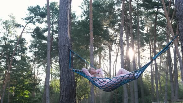 Young Girl Resting in a Hammock in the Middle of a Pine Forest