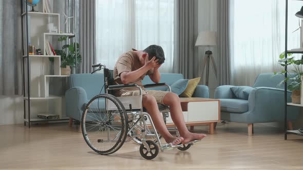 Disappointed Young Asian Boy Sitting In A Wheelchair In Living Room At The House