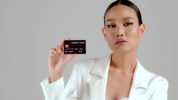 Beautiful Asian businesswoman showing credit card and looking at camera