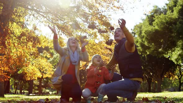 mother dad and daughter throwing leaves outdoors