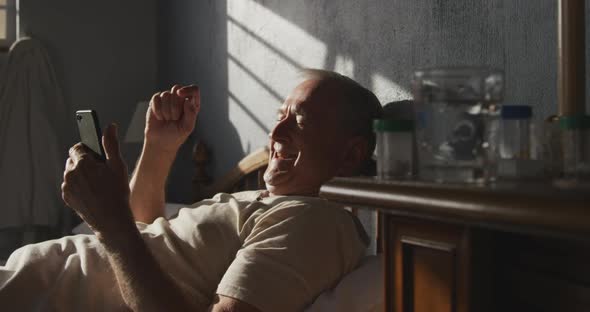 Senior man using digital tablet on bed