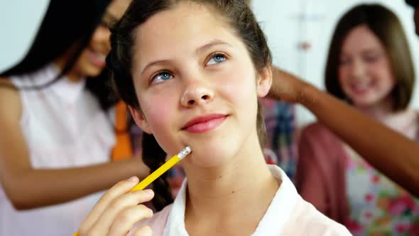 Thoughtful schoolgirl holding pencil in laboratory