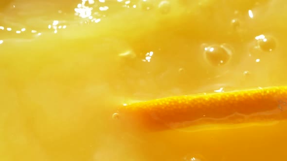 Macro Orange Fruit Slice Falling Down Into Fresh Orange Juice Drink, Slow Motion