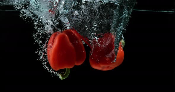 900455 Red Sweet Pepper, capsicum annuum, Vegetable falling into Water against Black Background, Slo