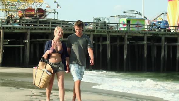 Teenage couple walking hand in hand on beach