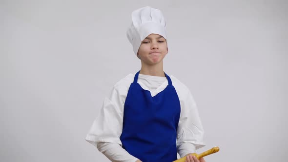 Dissatisfied Little Chef in Uniform Threatening with Rolling Pin Posing at White Background