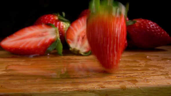 Ripe Strawberries Falling on a Wet Wooden Board