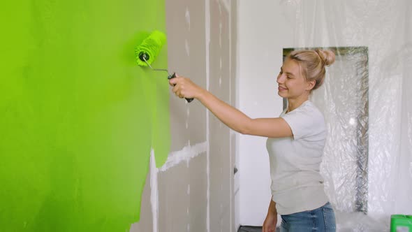 A Happy Woman Paints the Wall Green, a Guy Comes Up To Her and Gives Her a Five