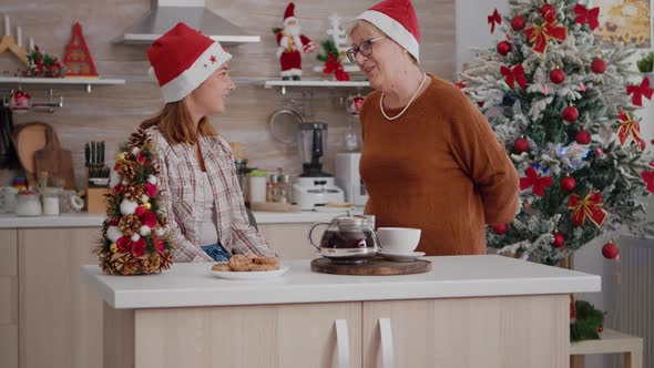 Grandmother Bringing Wrapper Present Gift with Ribbon on It to Granddaughter Enjoying Christmastime