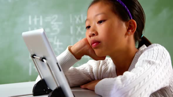 Schoolgirl using digital tablet in classroom at school