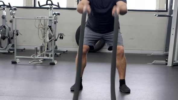 Male athlete uses two ropes to exercise his upper body. He waves the ropes in a rhythmic motion. NOR