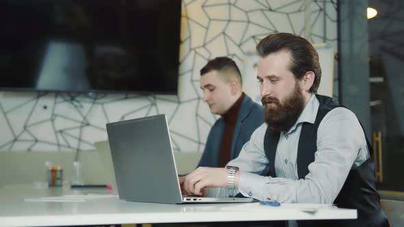 An Image of Two Programmers Working on a Laptop and a Tablet