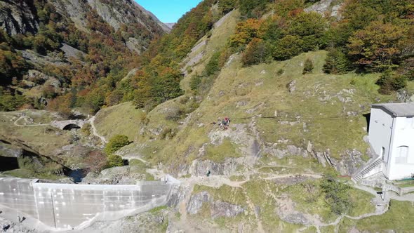 Lac d'Oô artificial lake in the French Pyrenees with hikers on the dam wall and man walking dog, Aer