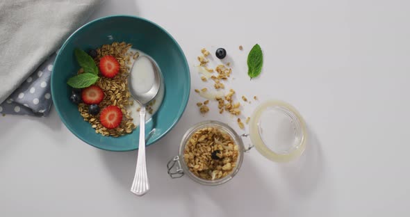 Video of cereals and fruit in ceramic bowl on white kitchen worktop