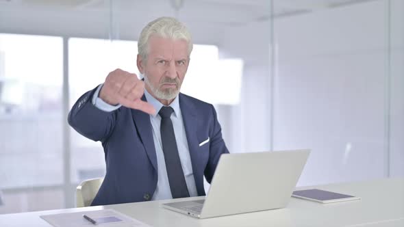 Old Businessman Doing Thumbs Down in Office