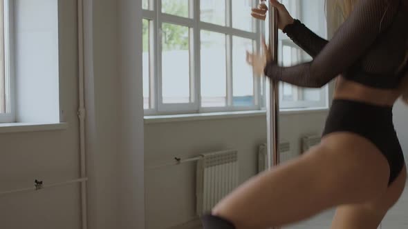 Flexible Woman Dancing on Pole in Studio