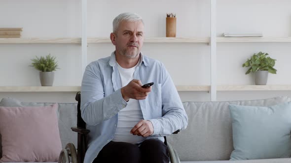 Discontented Disabled Man Watching TV Switching Channels At Home