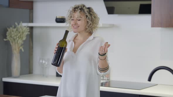 Portrait of Relaxed Smiling Happy Young Woman Smelling Wine in Bottle Smiling