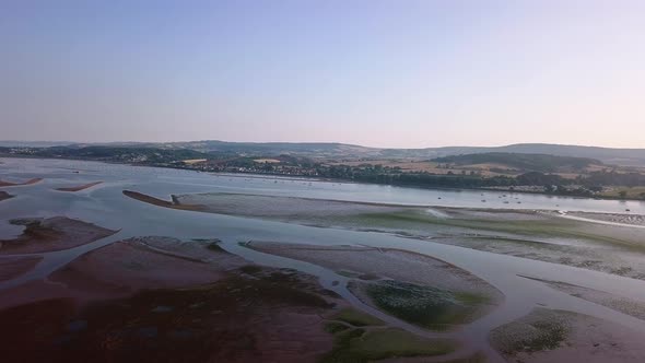 Flying over the beautiful landscape of Lympstone beach. The sky is clear, the hills and mountains in