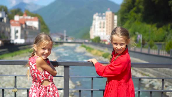 Back View of Girls on the Embankment of a Mountain River in a European City