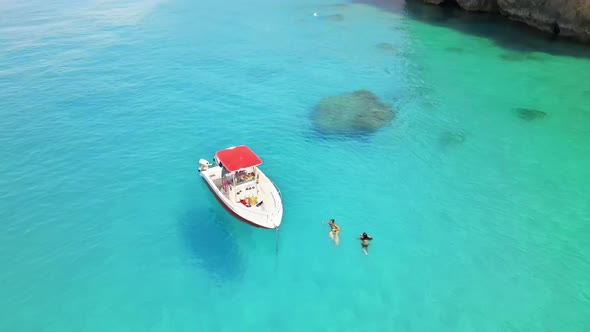 Aerial drone view of a moored boat near the coast of Zakynthos, Greece. Two women swimming