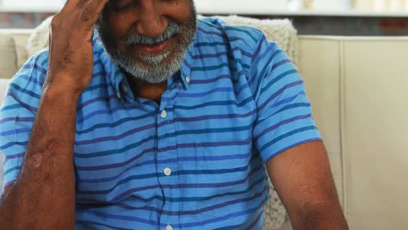 Tense senior man sitting on sofa in living room