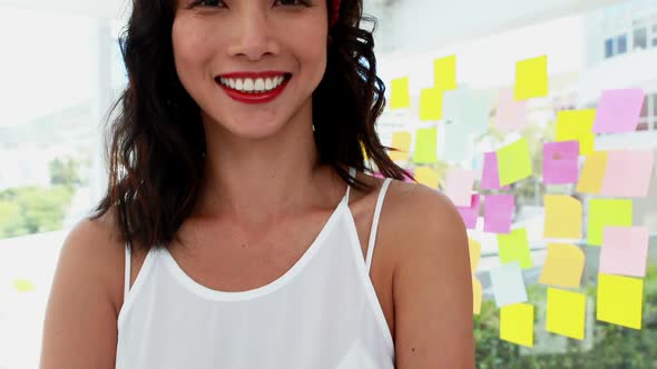 Smiling female executive standing with arms crossed in office 