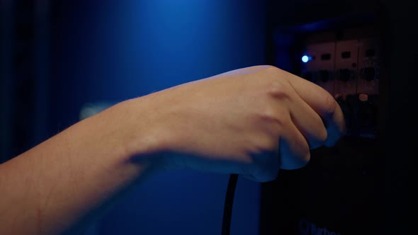 Closeup of a Man's Hand That Connects a Speaker with a Cable