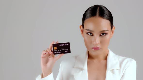 Beautiful Asian businesswoman showing credit card and looking at camera