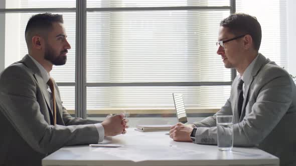 Two Businessmen Speaking and Shaking Hands in Office