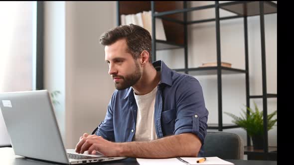 Handsome Bearded Male Entrepreneur in Casual Wear Using Laptop for Remote Work