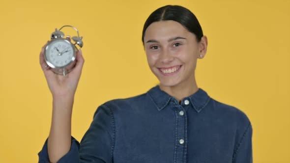 Latin Woman Holding a Clock Yellow Background