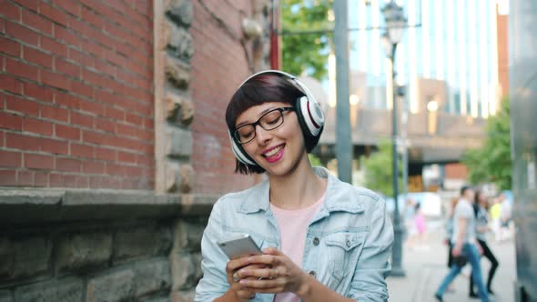 Slow Motion of Girl Listening To Music in Headphone Using Smartphone Outdoors