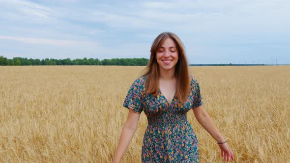 Happy Girl Goes Across Field Touches Ears of Wheat