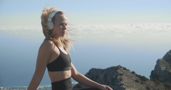 Young Woman Listening To Headphones On Mountaintop