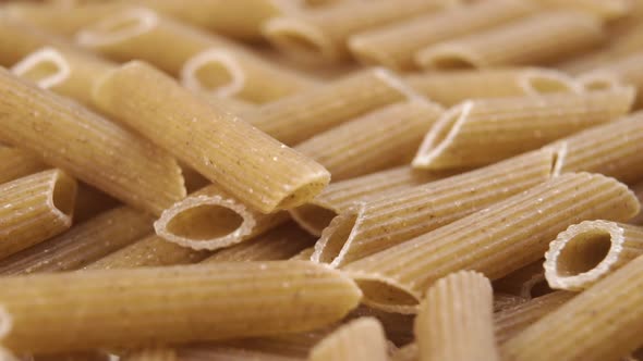 Raw integral whole grain penne pasta falling in slow motion