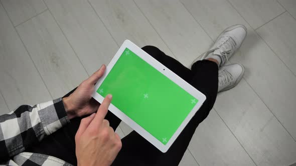 Man Sitting on Chair Looking at Digital Tablet with Green Screen Chroma Key