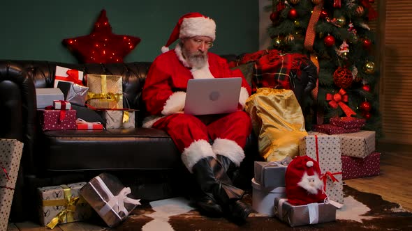 Santa Claus Orders Gifts on the Internet Using a Laptop