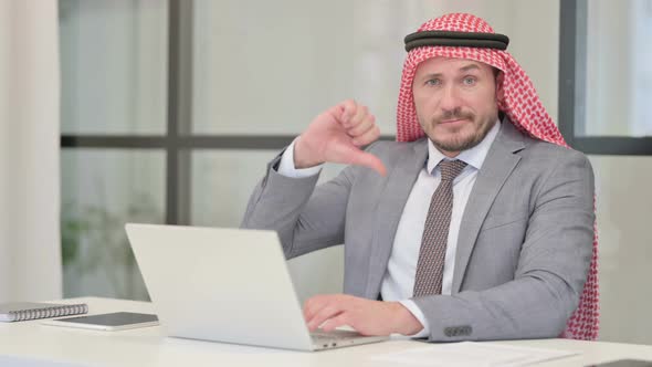 Middle Aged Arab Businessman Showing Thumbs Down Sign While using Laptop in Office