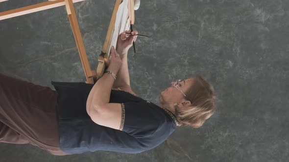 Elderly Woman Painting at Easel in Studio