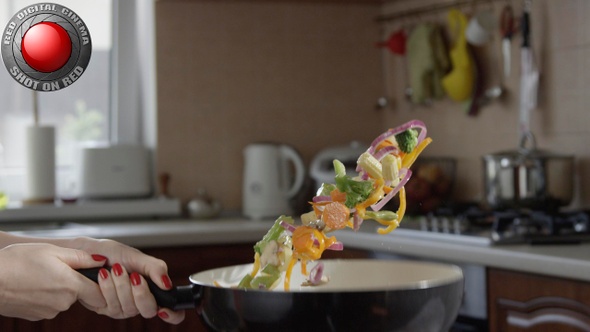 Woman Tossing Vegetables On A Frying Pan In The Kitchen In Slow Motion Shot On Red Camera