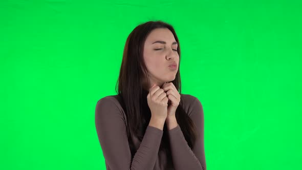 Attractive Girl Looking with Tenderness and Folded Arms in Front of Her. Green Screen