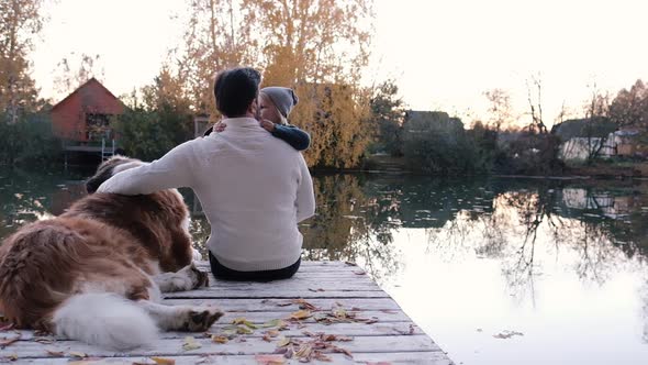 Friendship Concept, a Man with His Son in His Arms and a Dog Sitting Together. Little Boy Hugs Dad