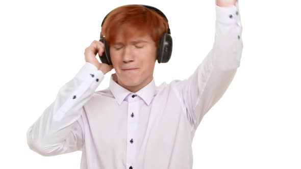 Ginger Young Handsome Caucasian Man Listening Music Through Big Headphones and Jumping on White