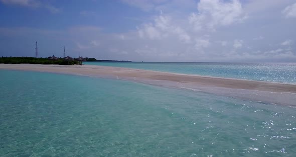 Wide flying abstract view of a white sand paradise beach and blue water background in hi res 4K