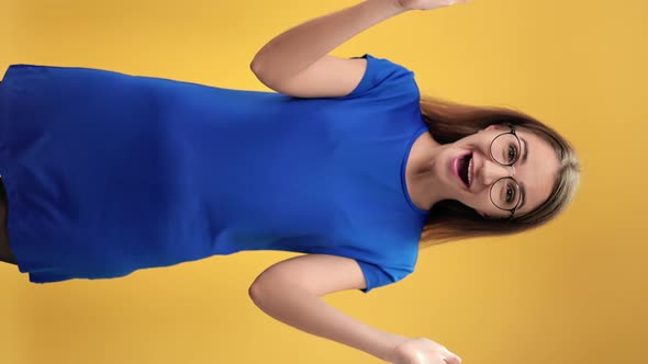 VERTICAL VIDEO POV Shocked Excited Woman Blue Dress Screaming Wow Posing Isolated on Orange Studio