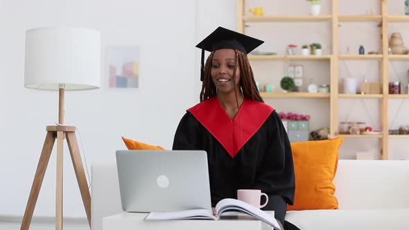 Black Woman in Cap and Gown Waving Greeting Person in Video Call Spbi