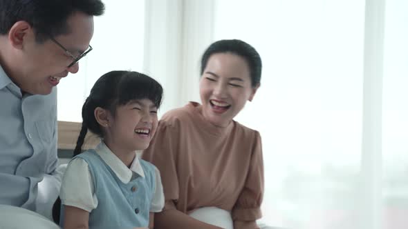 Father and mother are teaching their daughter homework at home, cosy family and education concept