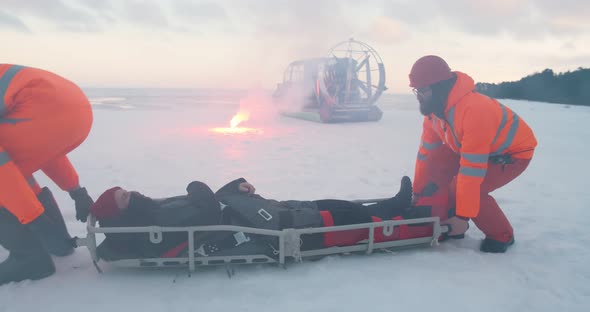 Lifeguards Carrying Victim on Stretcher and Loading in Hovercraft on Frozen Lake